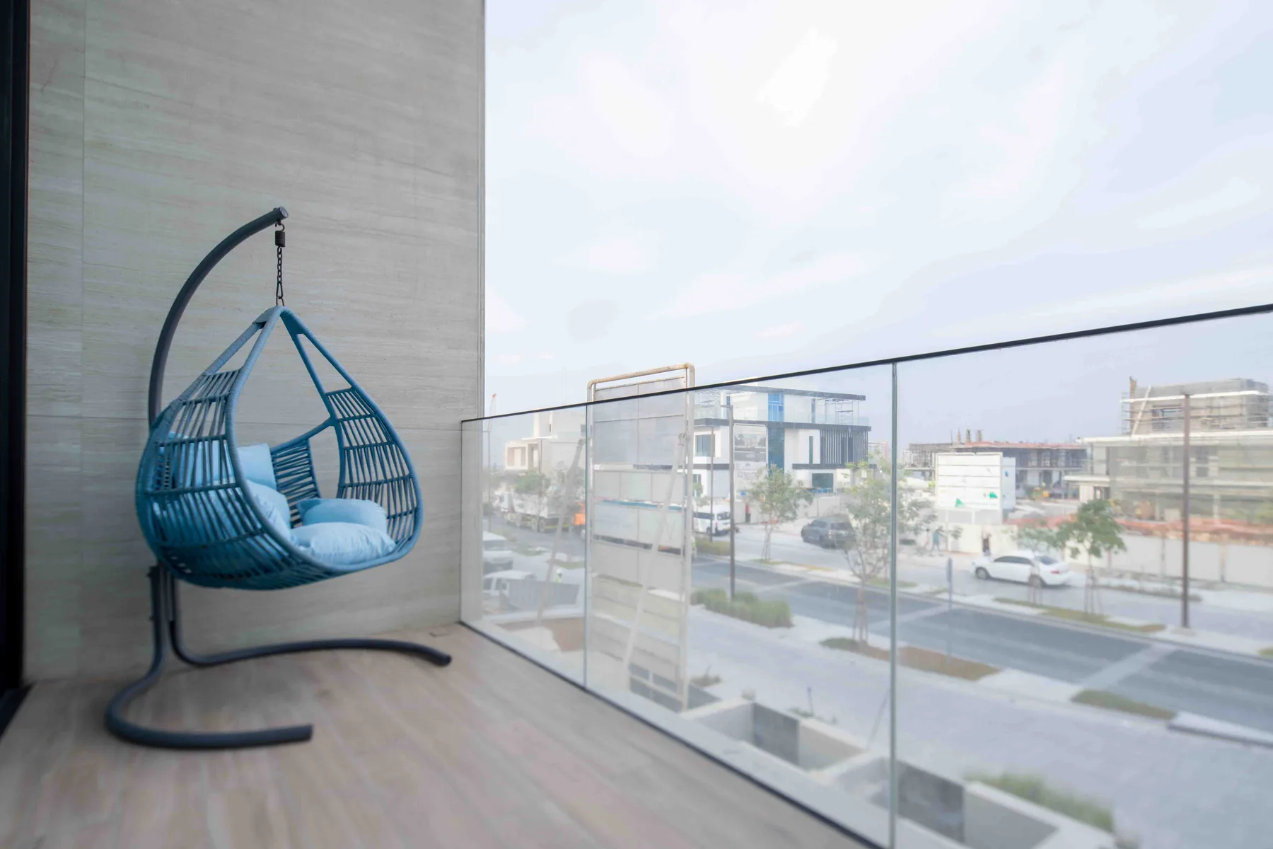 Un balcón con un asiento colgante da a una calle y edificios cercanos.