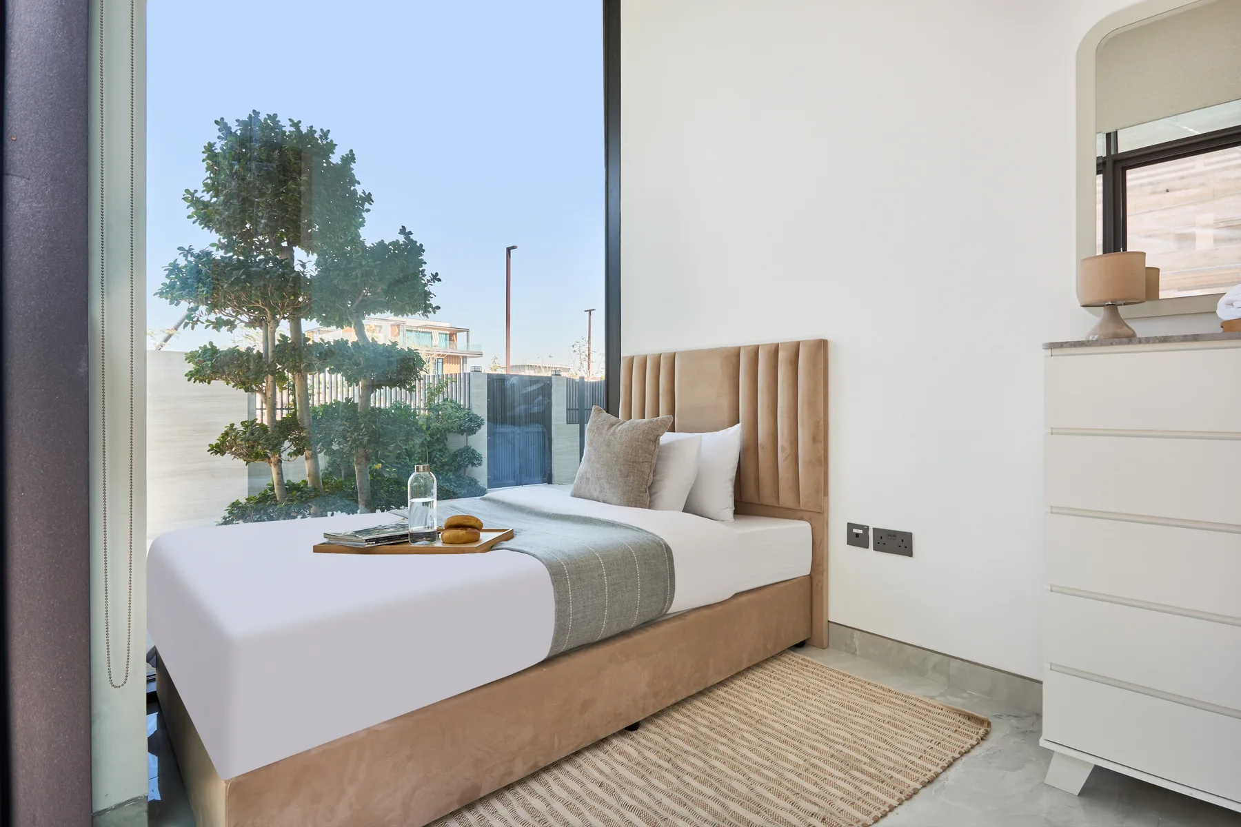 Un dormitorio con una cama bien arreglada junto a una ventana grande.