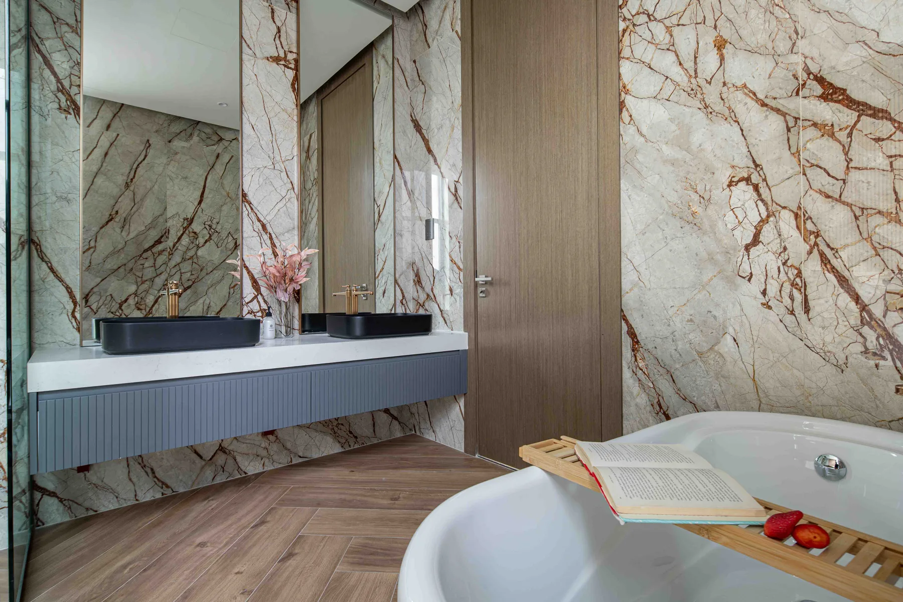Un baño con bañera, lavabo y grandes paneles de pared con vetas decorativas.