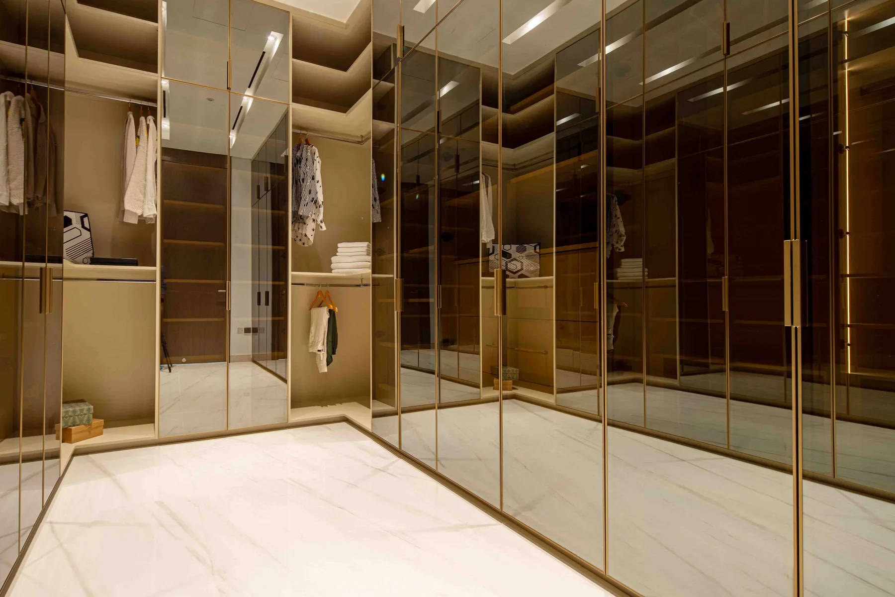 Un amplio vestidor con armarios con espejo y estantes abiertos.