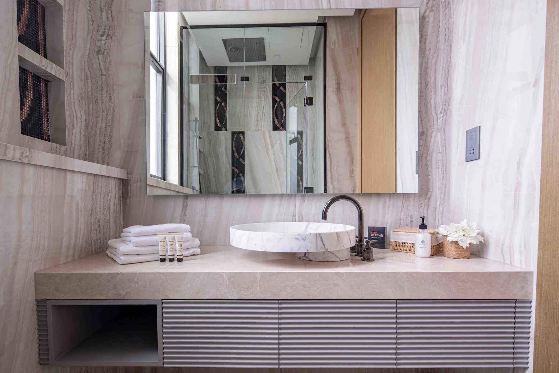 Un tocador de baño con lavabo sobre encimera, superficie y un espejo grande.