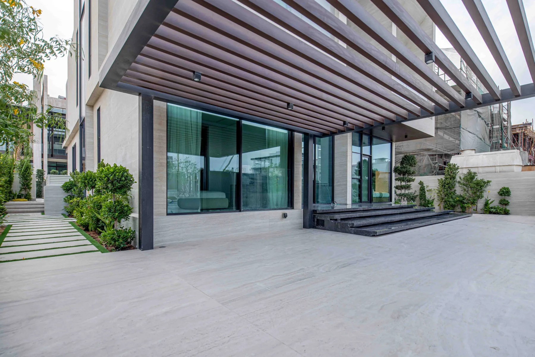 Un patio de una casa moderna con grandes ventanales y una cubierta de listones.