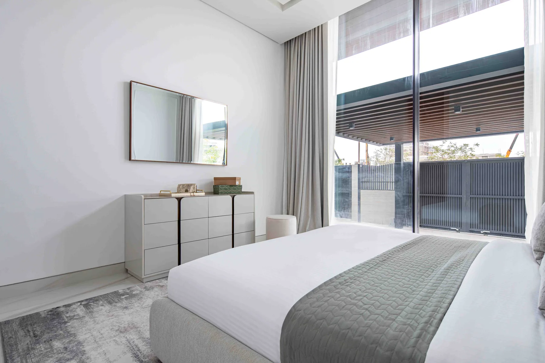 Un dormitorio luminoso con una cama bien hecha y grandes ventanas.