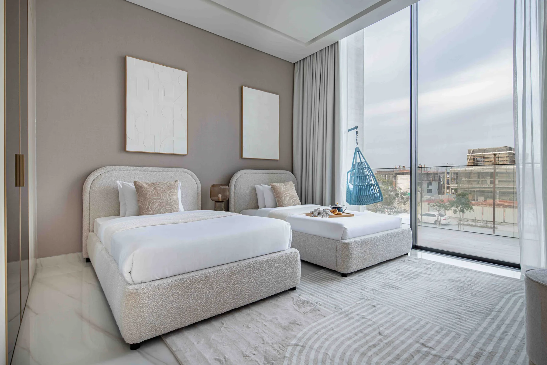 Un dormitorio luminoso con dos camas junto a ventanas de piso a techo.