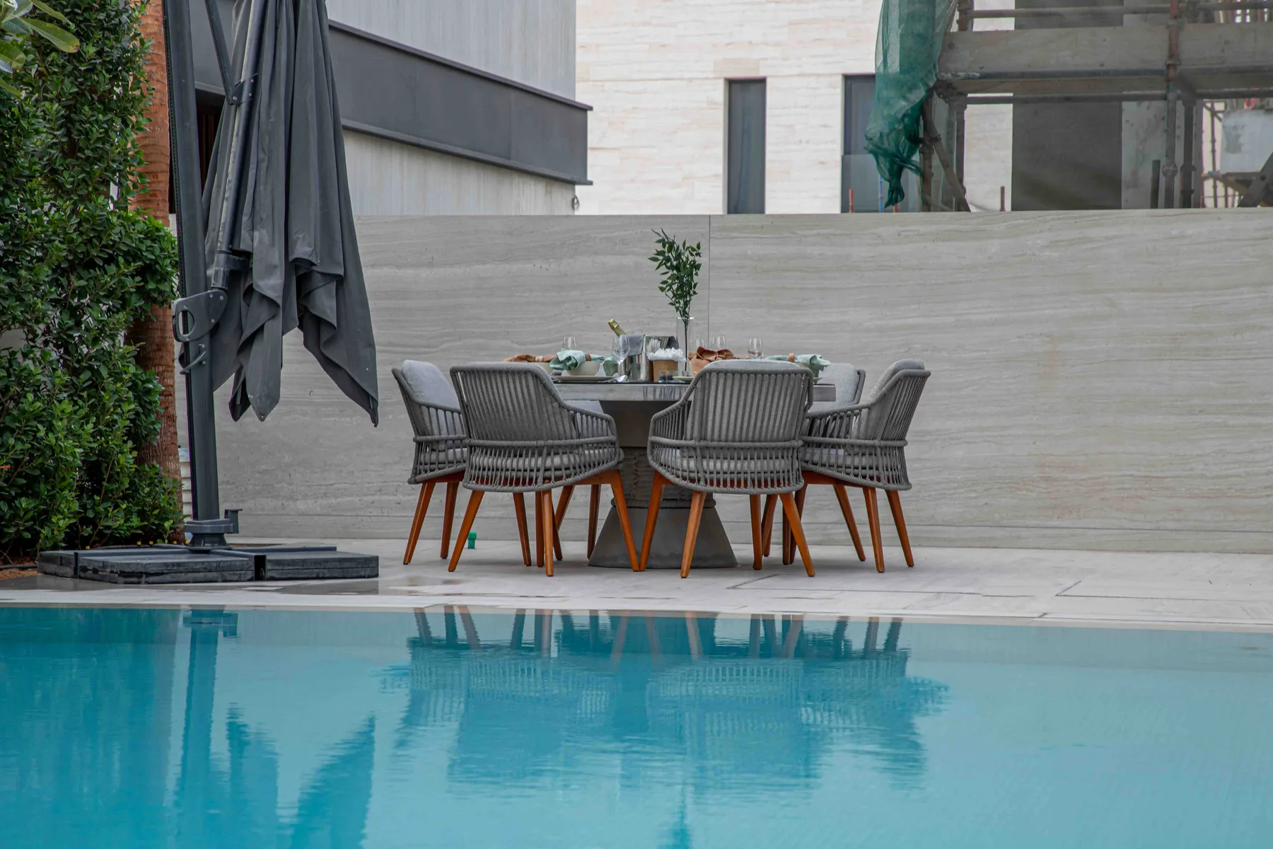 Un comedor al aire libre junto a una piscina, con una mesa y asientos.