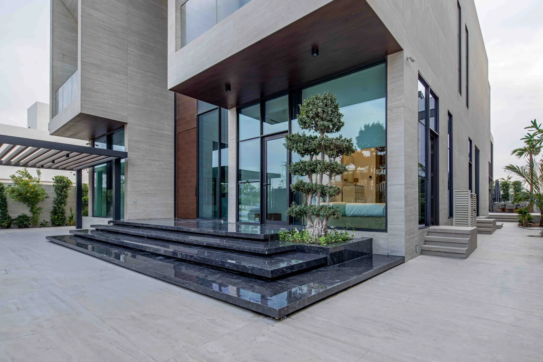 Exterior de una casa moderna con grandes ventanales y una terraza elevada en la entrada.