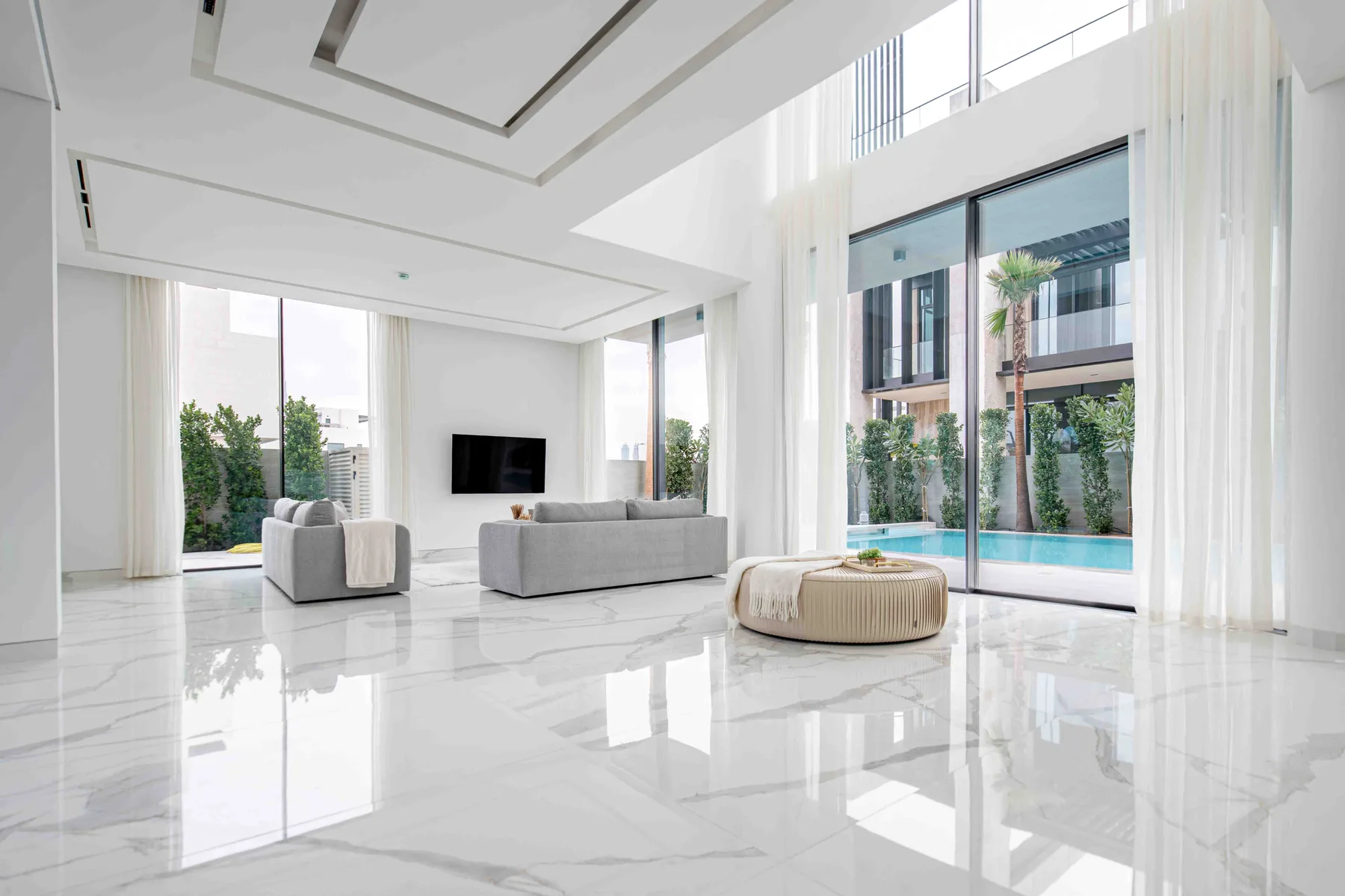 Una sala luminosa con asientos junto a ventanales que dan a una piscina.