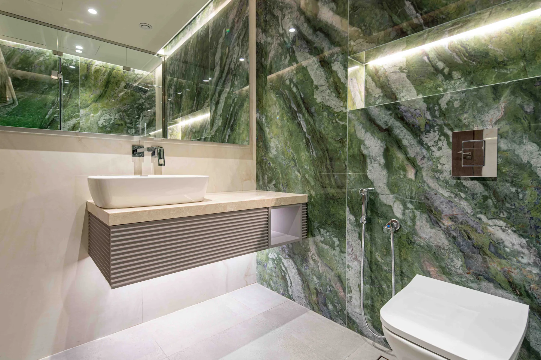 Un baño moderno con lavabo sobre encimera, tocador con espejo y ducha.
