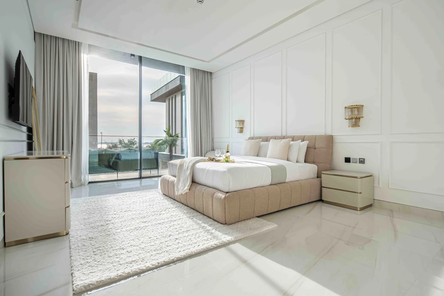 Un dormitorio luminoso con una cama grande junto a ventanales.