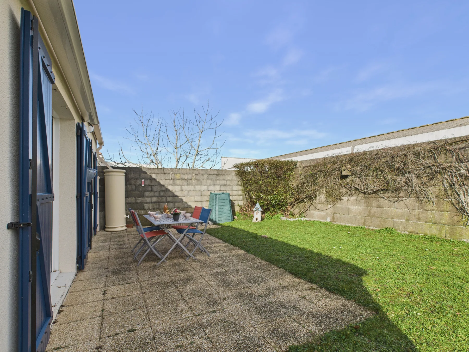 A paved patio with outdoor seating beside a grassy yard.