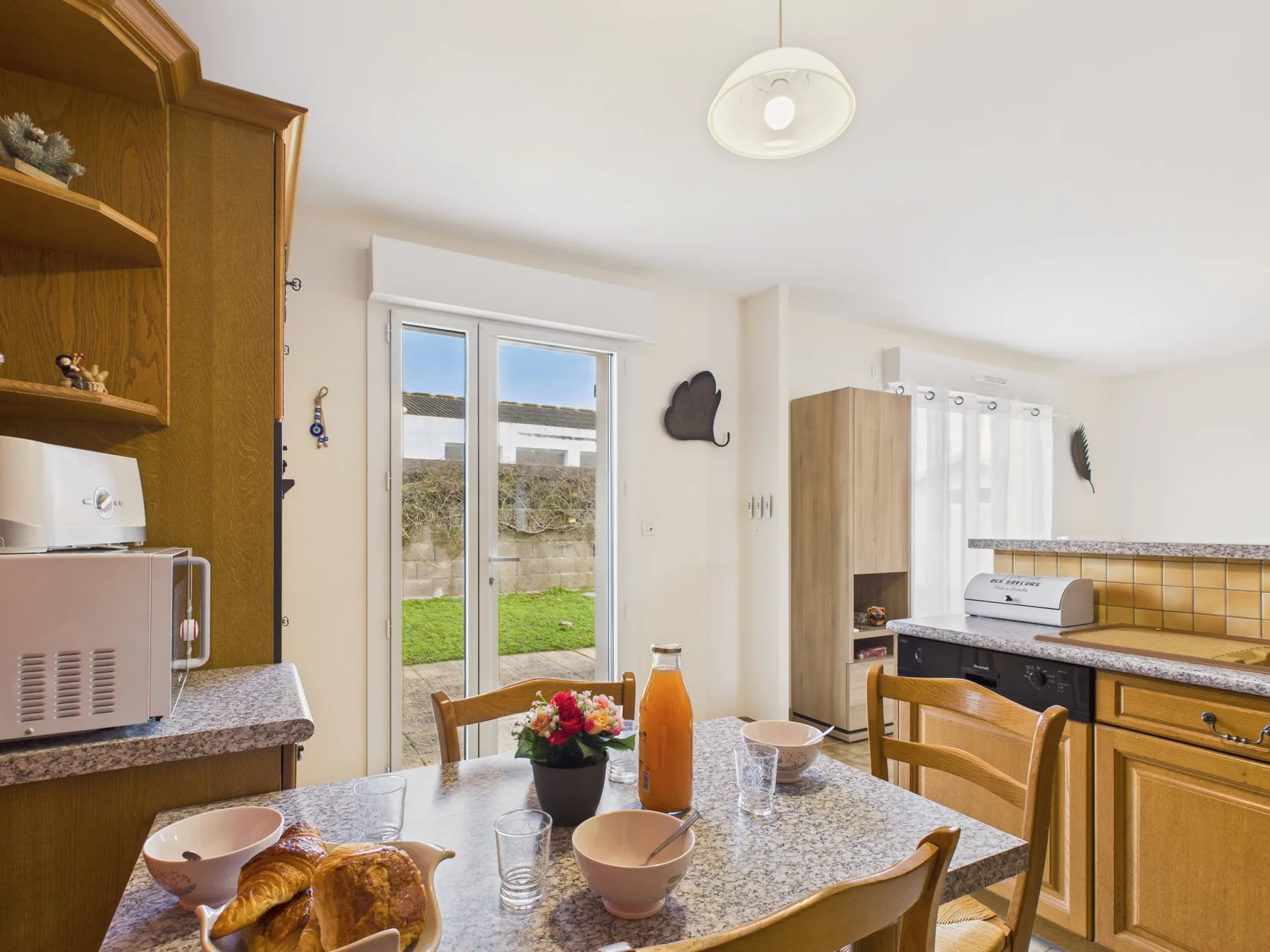 A bright kitchen and dining area with a table beside glass patio doors.