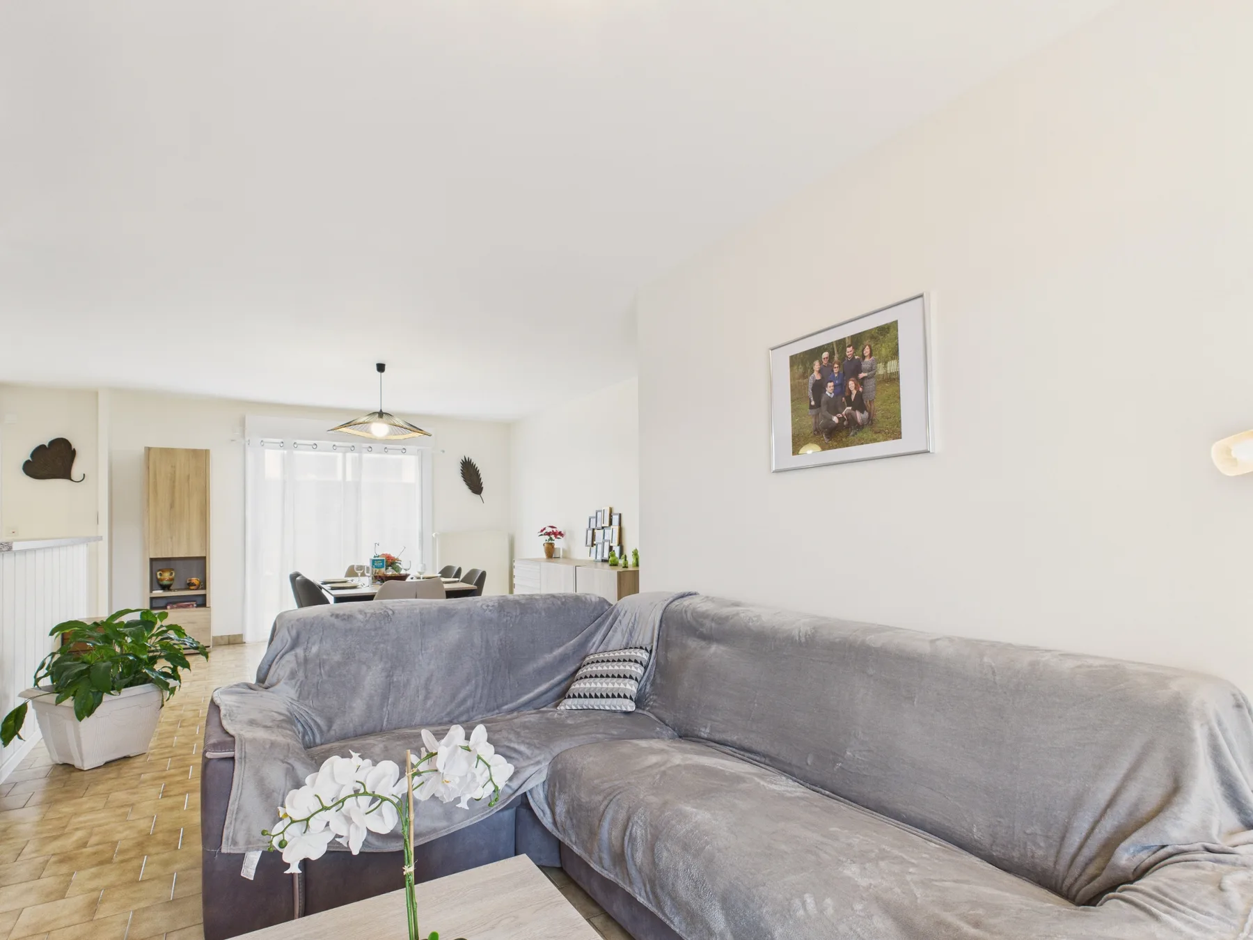 A bright living room with gray seating and a dining area beyond.