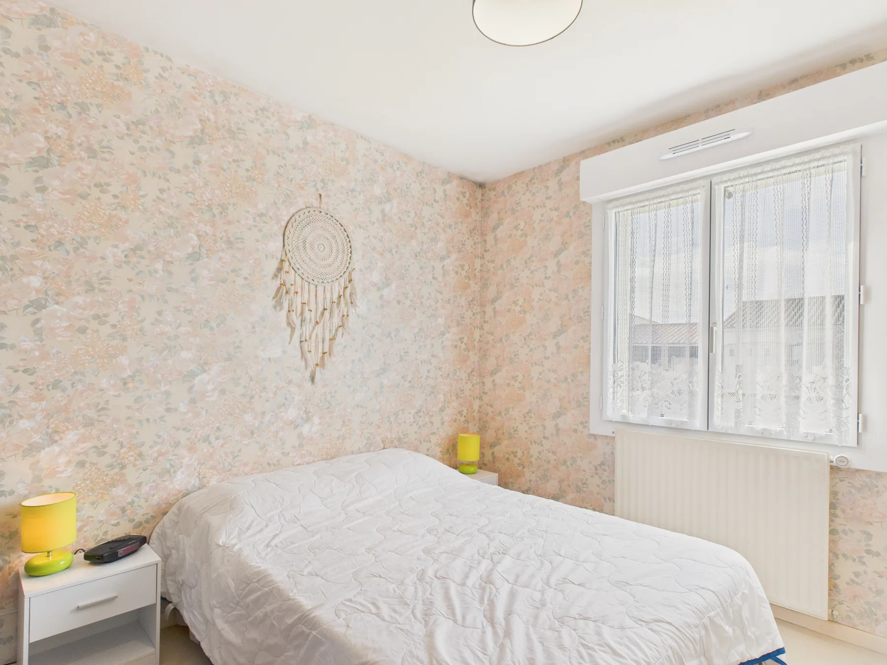 A bedroom with a bed beside a window.