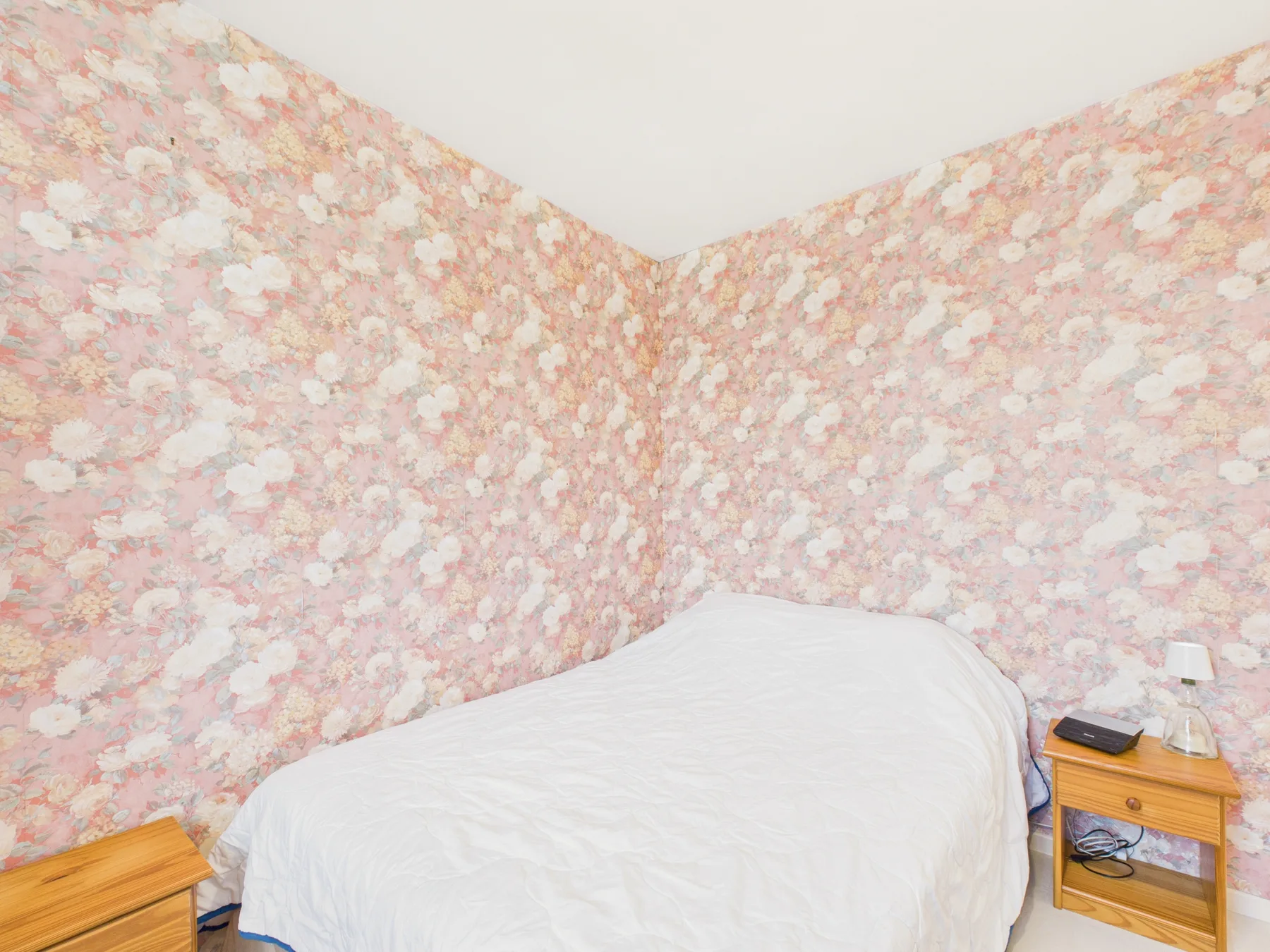 A bedroom with a bed against floral-patterned walls.
