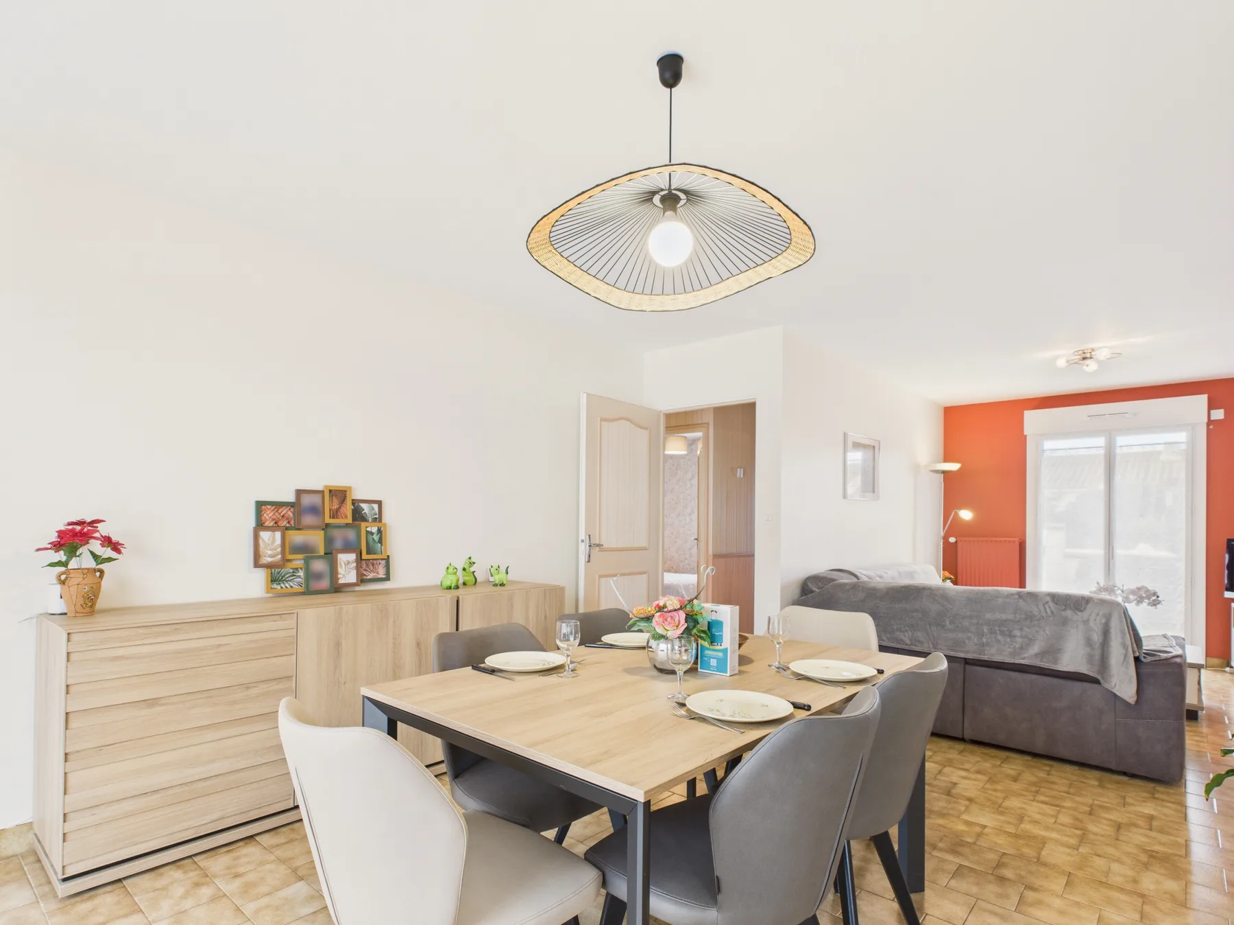 A dining area with a set table beside a living room and bright window.