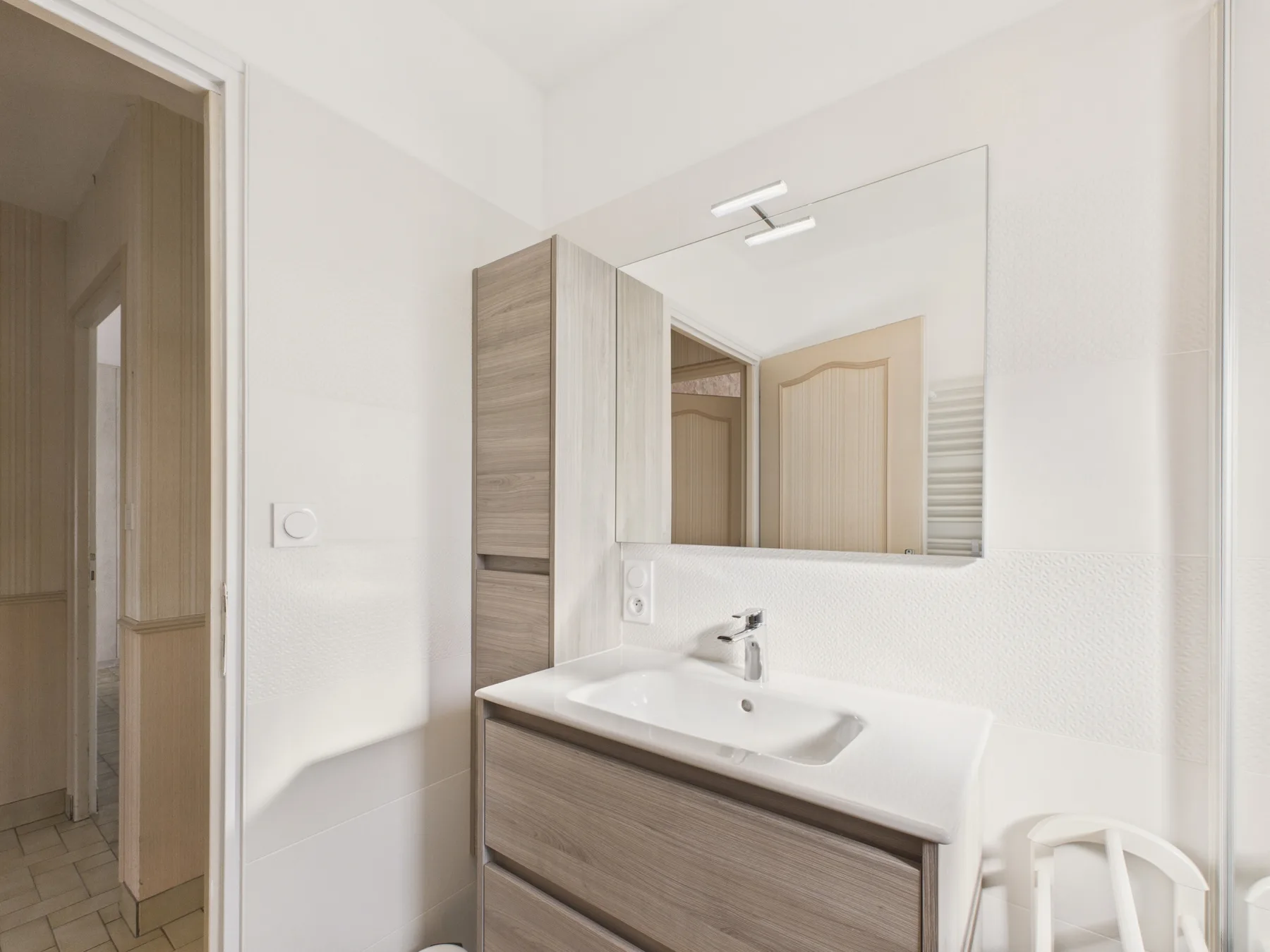 A bright bathroom with a wide sink and wall mirror.