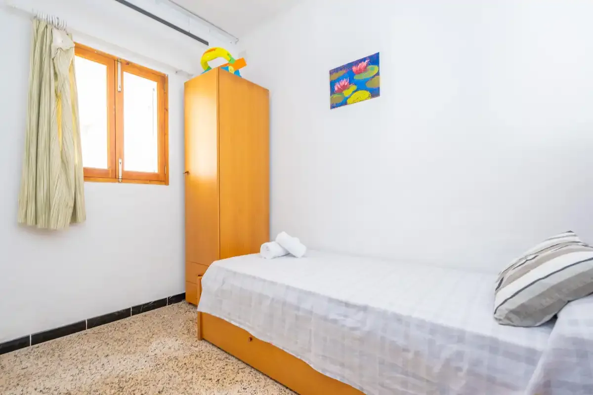 Un dormitorio sencillo con una cama individual, un armario y una ventana.