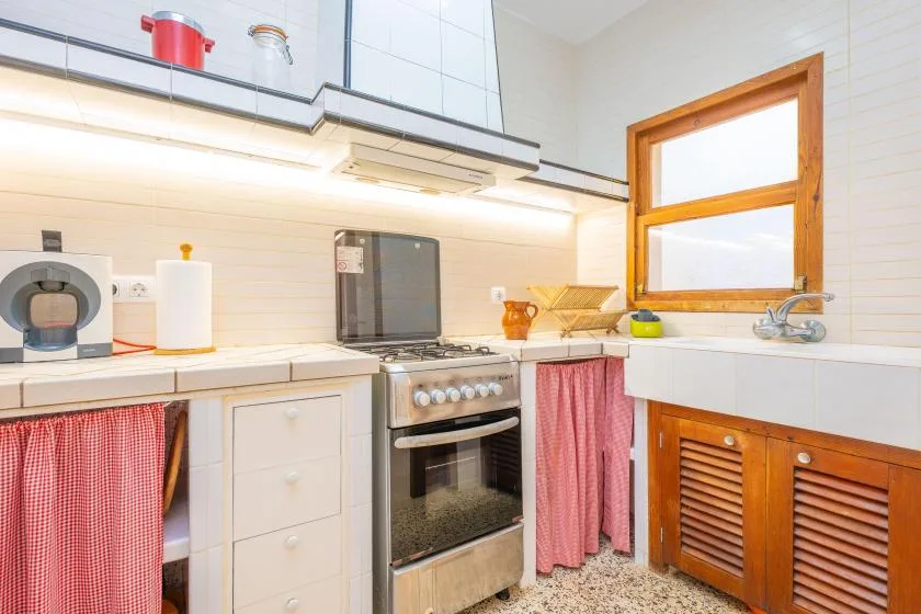 Una cocina luminosa con estufa, encimera y ventana con marco de madera.