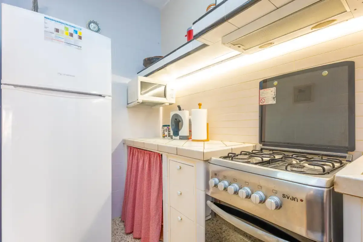 Una cocina compacta con refrigerador, encimera y estufa de gas.