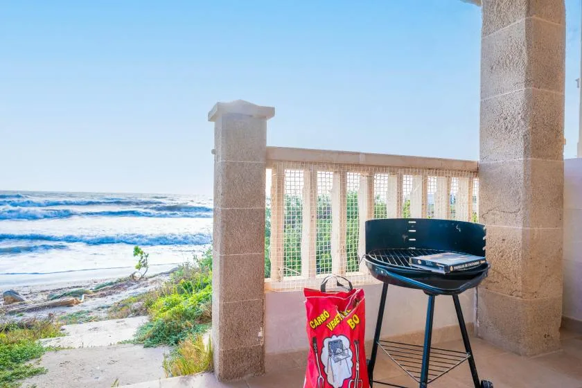 Una terraza junto al mar da al océano, con una parrilla junto a la barandilla.