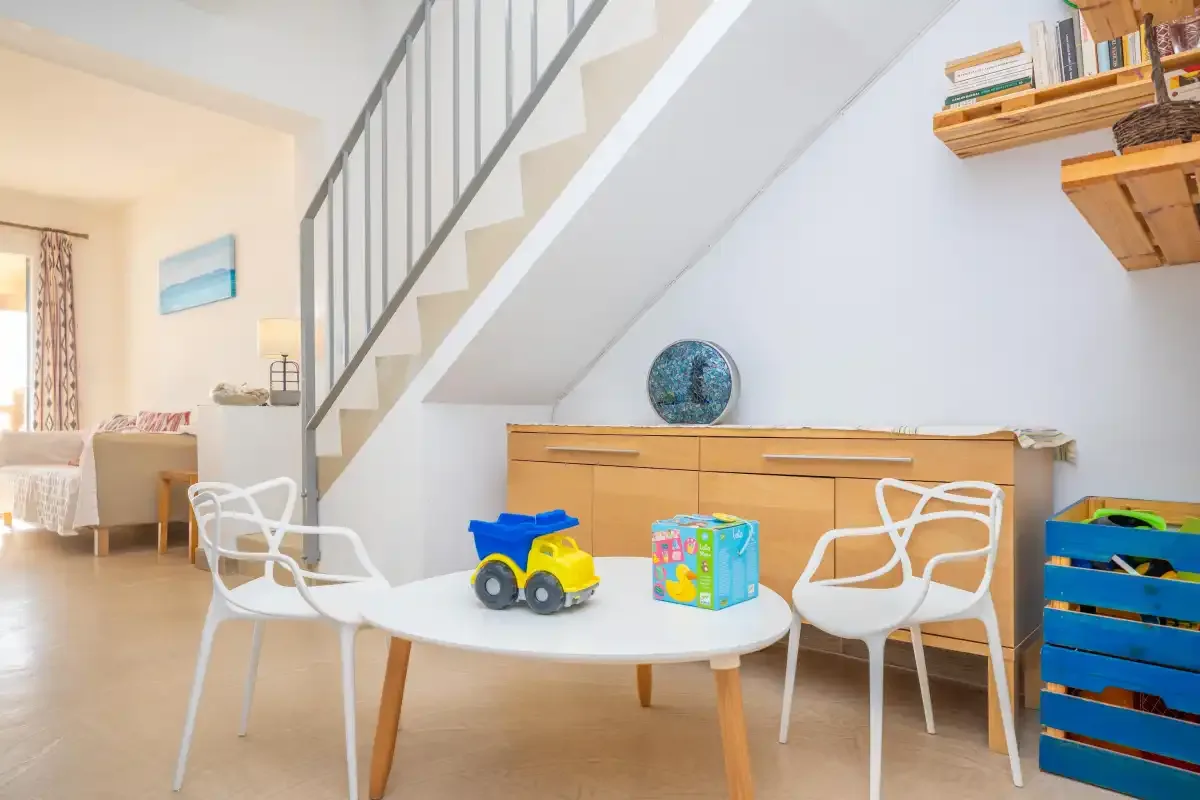 Una luminosa zona de estar con una mesa pequeña y asientos bajo una escalera.