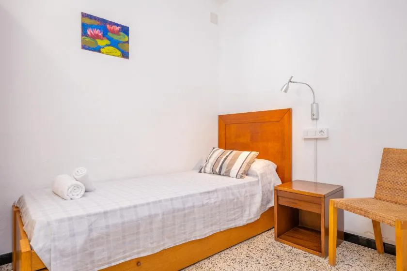 Un dormitorio con una cama de madera, almohadas a rayas y una mesita de noche.