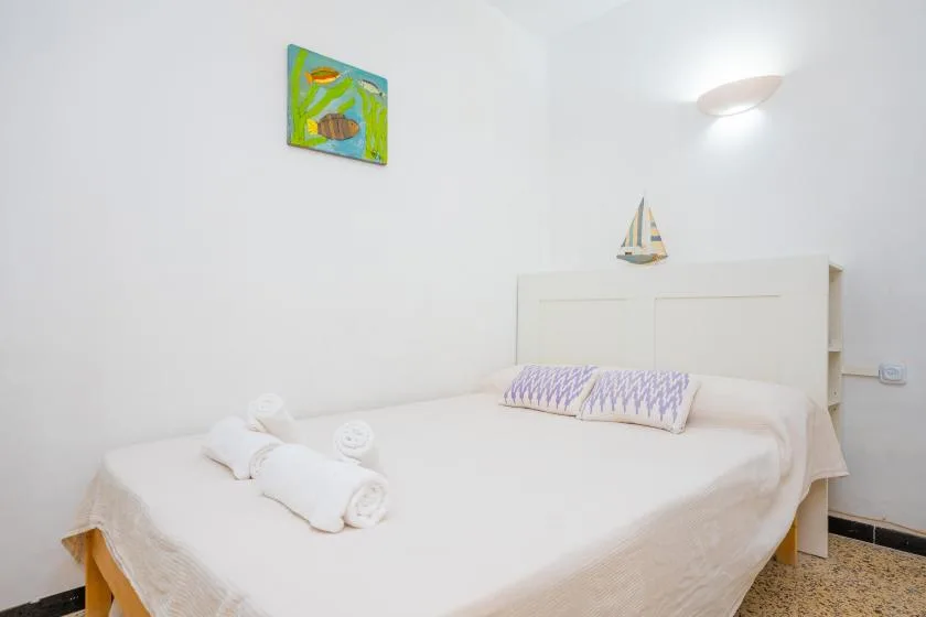 Un dormitorio luminoso con una cama bien tendida y arte colorido en la pared.