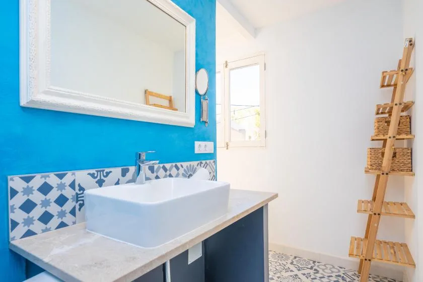 Un lavabo de baño con una pila sobrepuesta está frente a una pared azul.