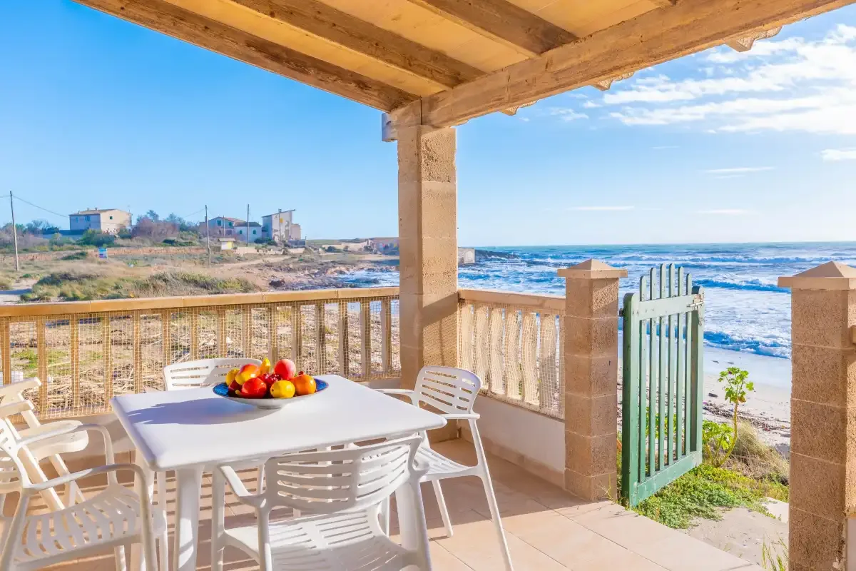Una terraza cubierta junto al mar con una mesa de comedor frente a la playa.