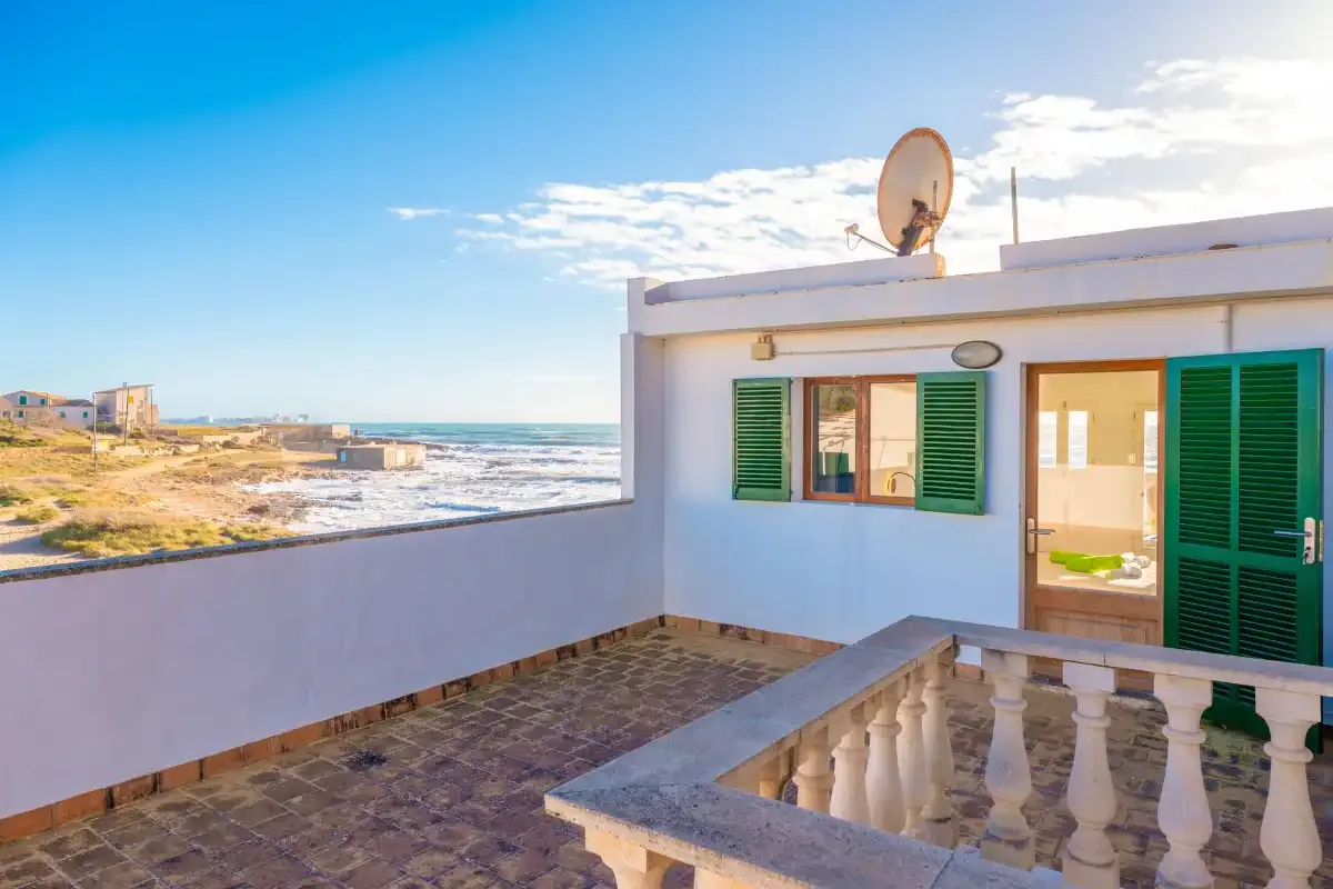 Una terraza junto al mar con contraventanas verdes y vistas a la costa.