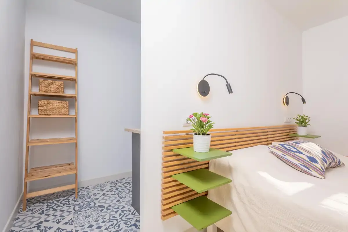 Un dormitorio con una cama, apliques de pared y una estantería de madera.