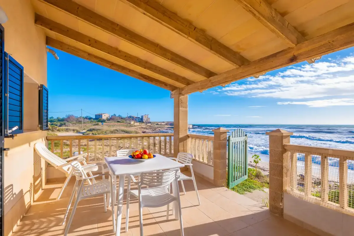 Una terraza cubierta junto al mar con una mesa de comedor frente al agua.