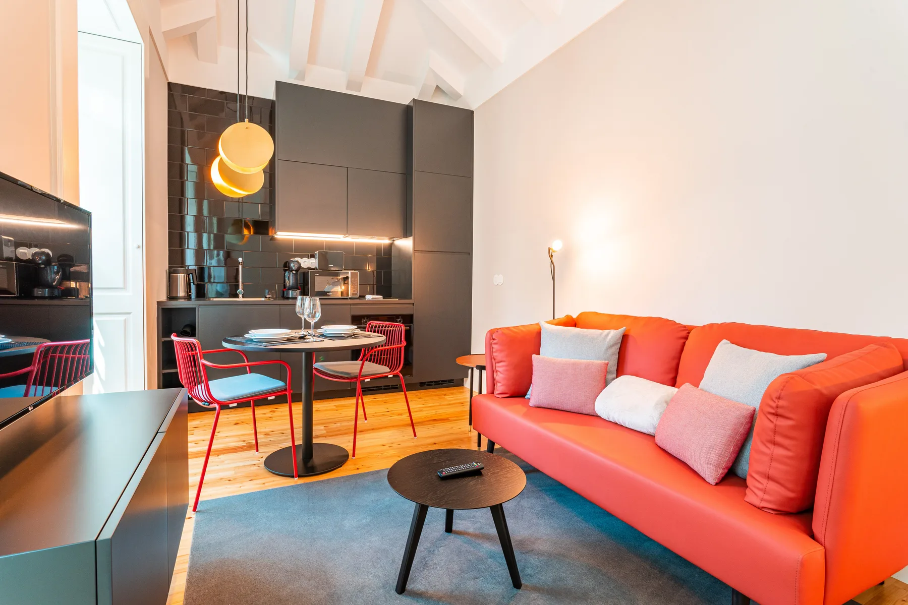 Una luminosa sala de estar tipo estudio con un sofá rojo y una mesa de comedor.