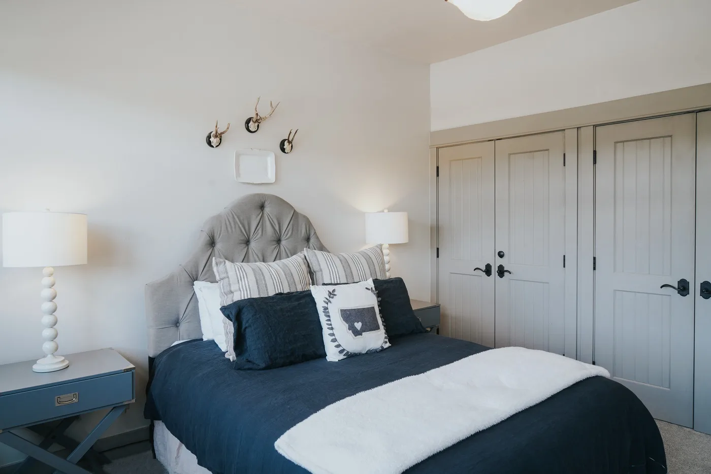 A bedroom with a neatly made bed and closed paneled doors.