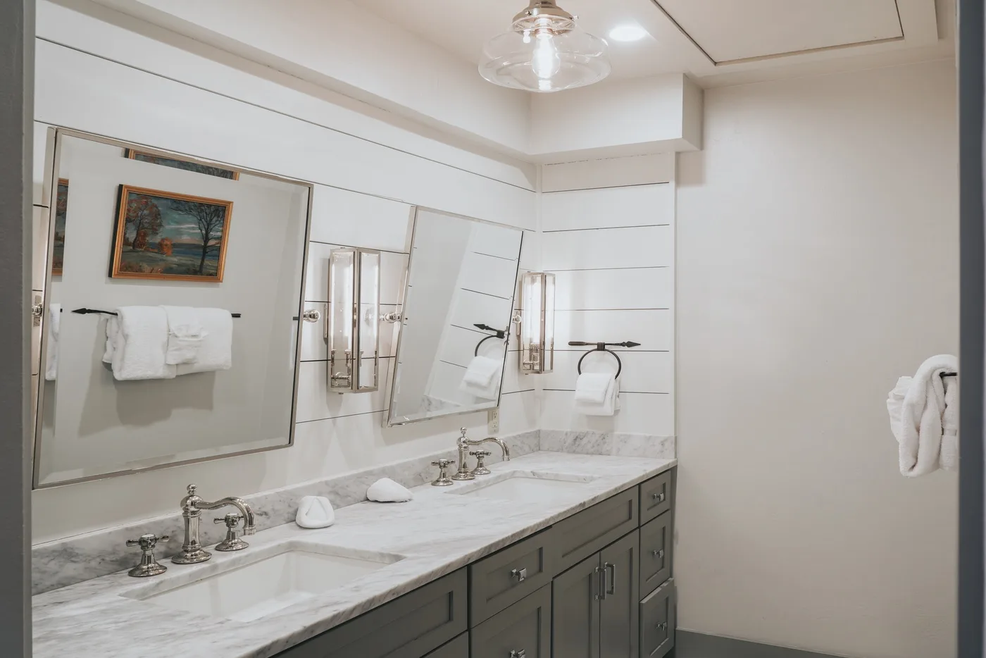 A bathroom vanity with a wide mirror, wall-mounted lights, and a long countertop.