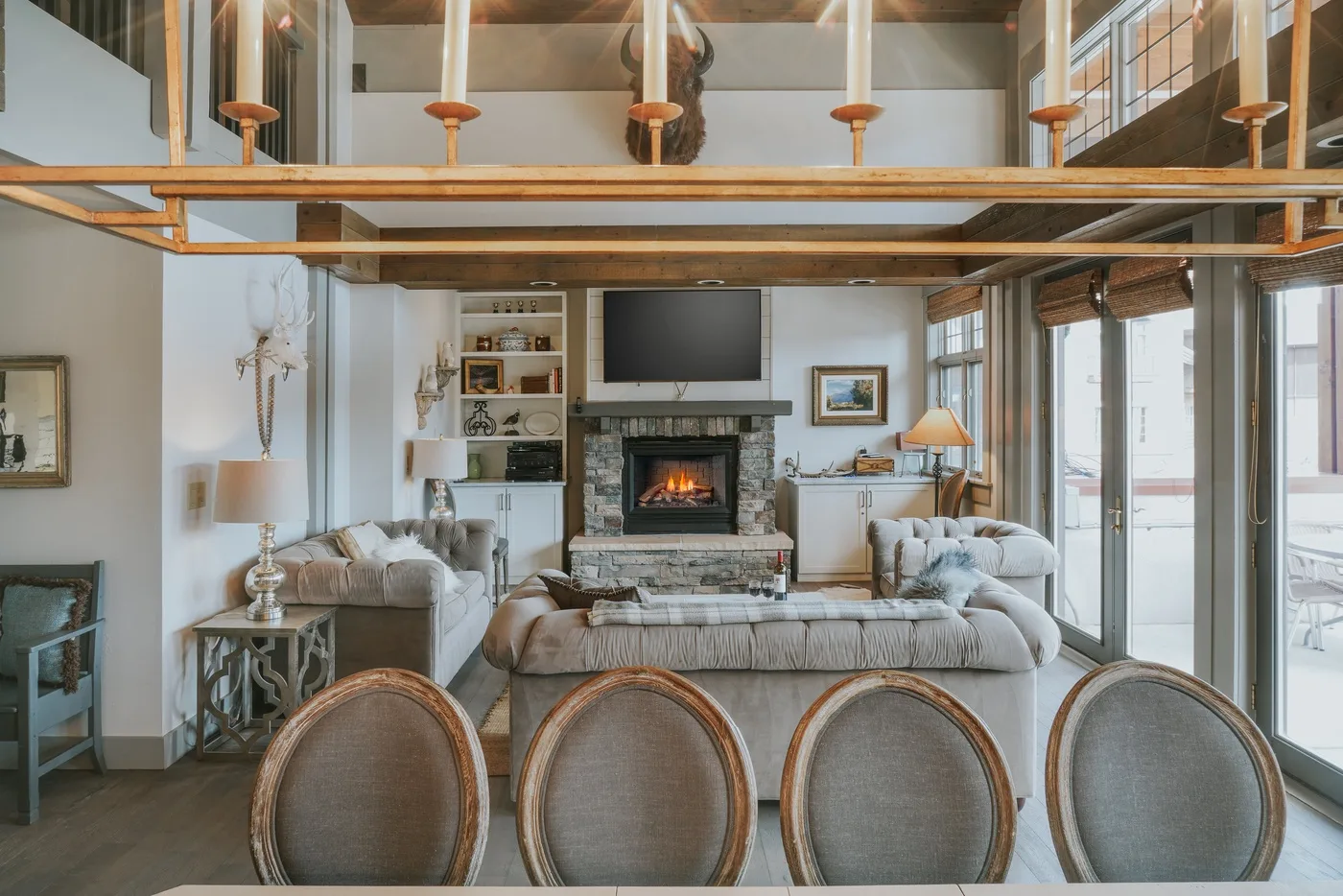A bright living room with sofas, a fireplace, and tall windows.