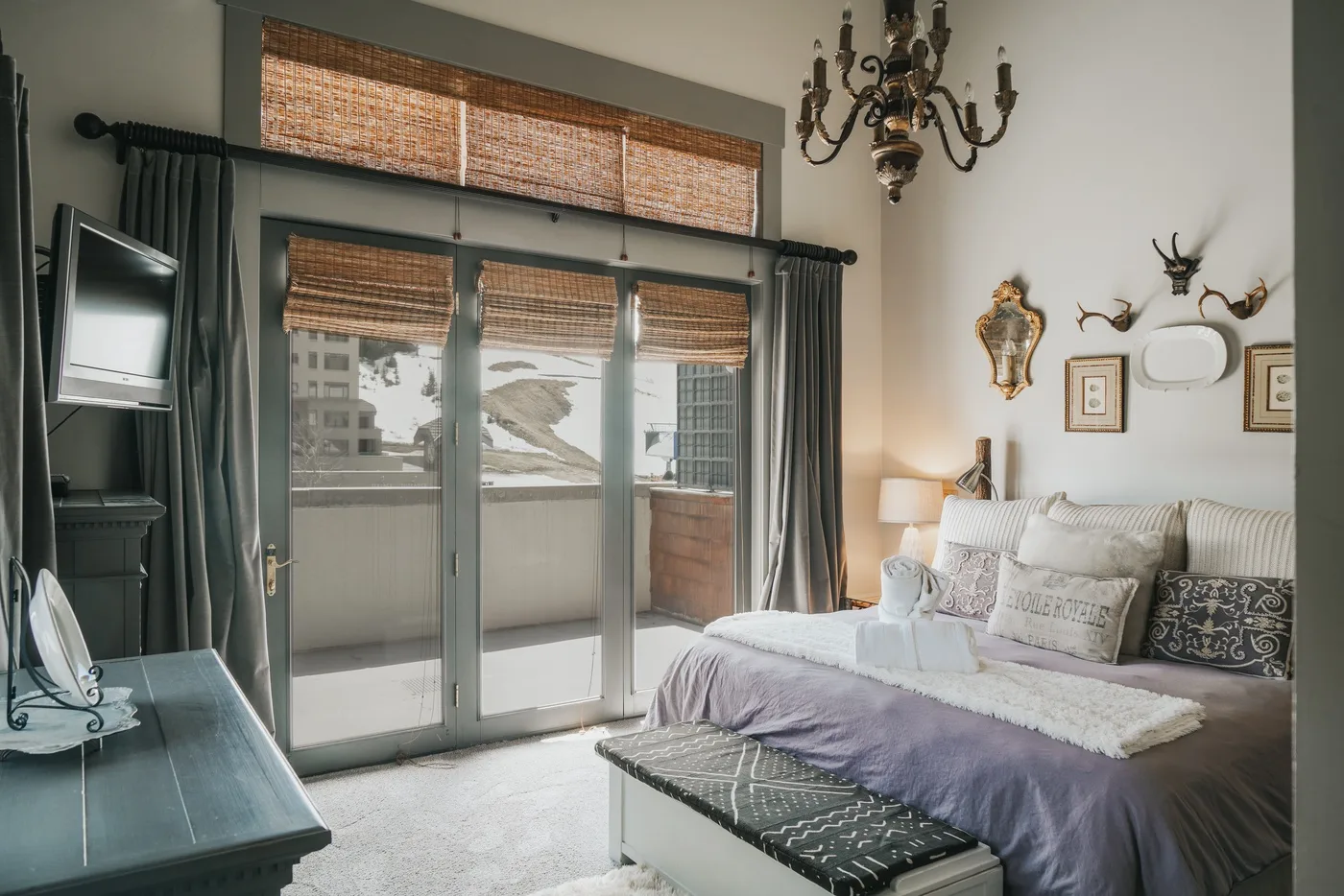 A bedroom with a bed, sliding glass doors, and a wall-mounted television.