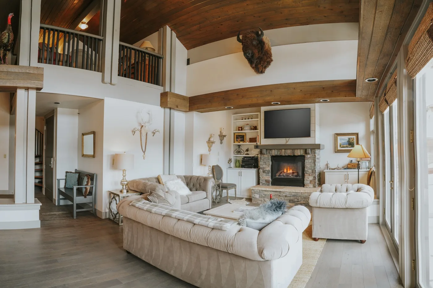 A spacious living room with seating arranged around a fireplace and television.