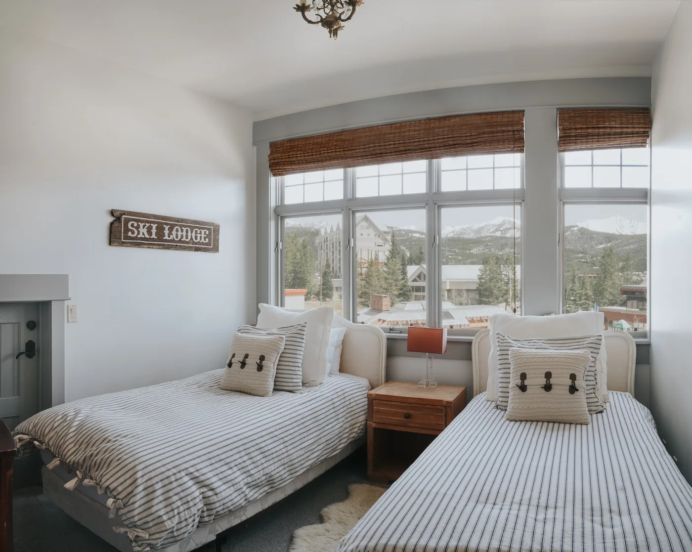 A bedroom with two beds beside large windows overlooking a mountain landscape.