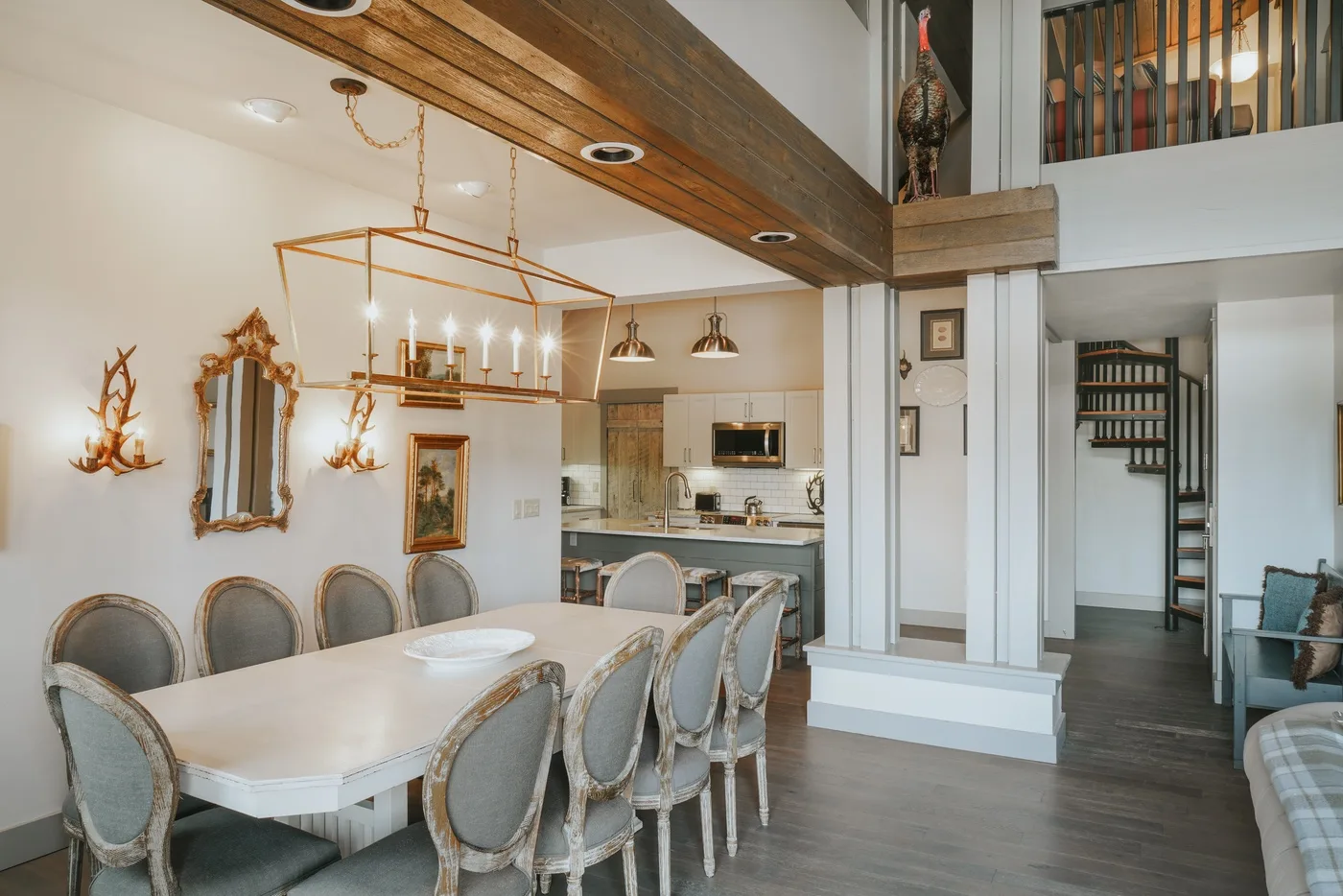 A dining area with a long table sits beside an open kitchen.