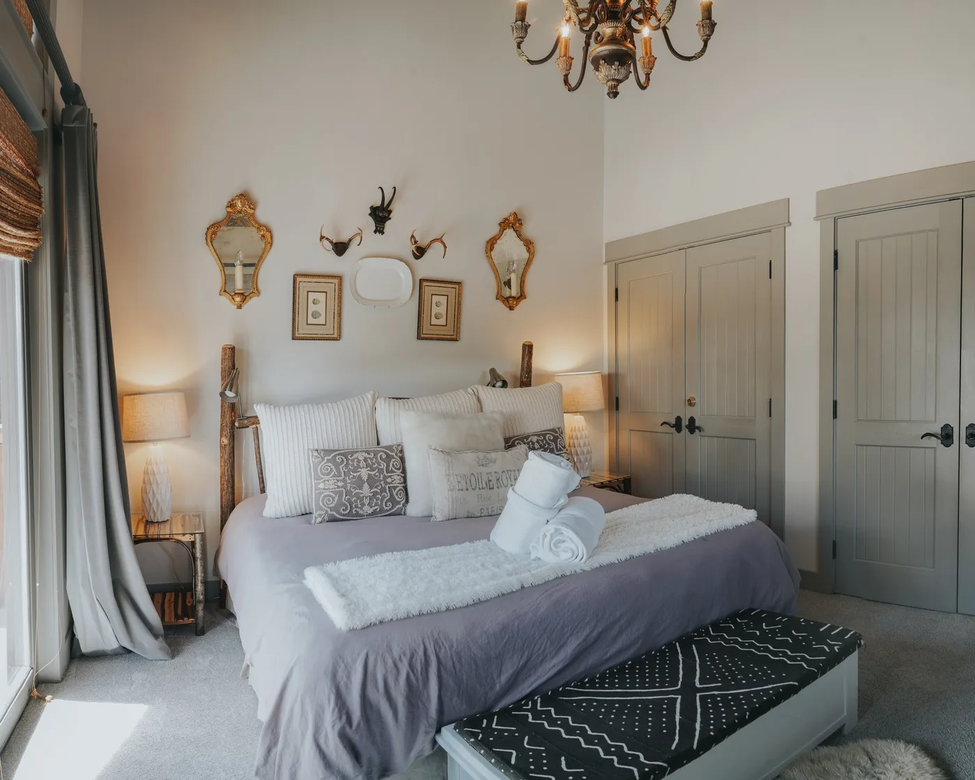 A bedroom with a neatly made bed, decorative pillows, and paneled doors.