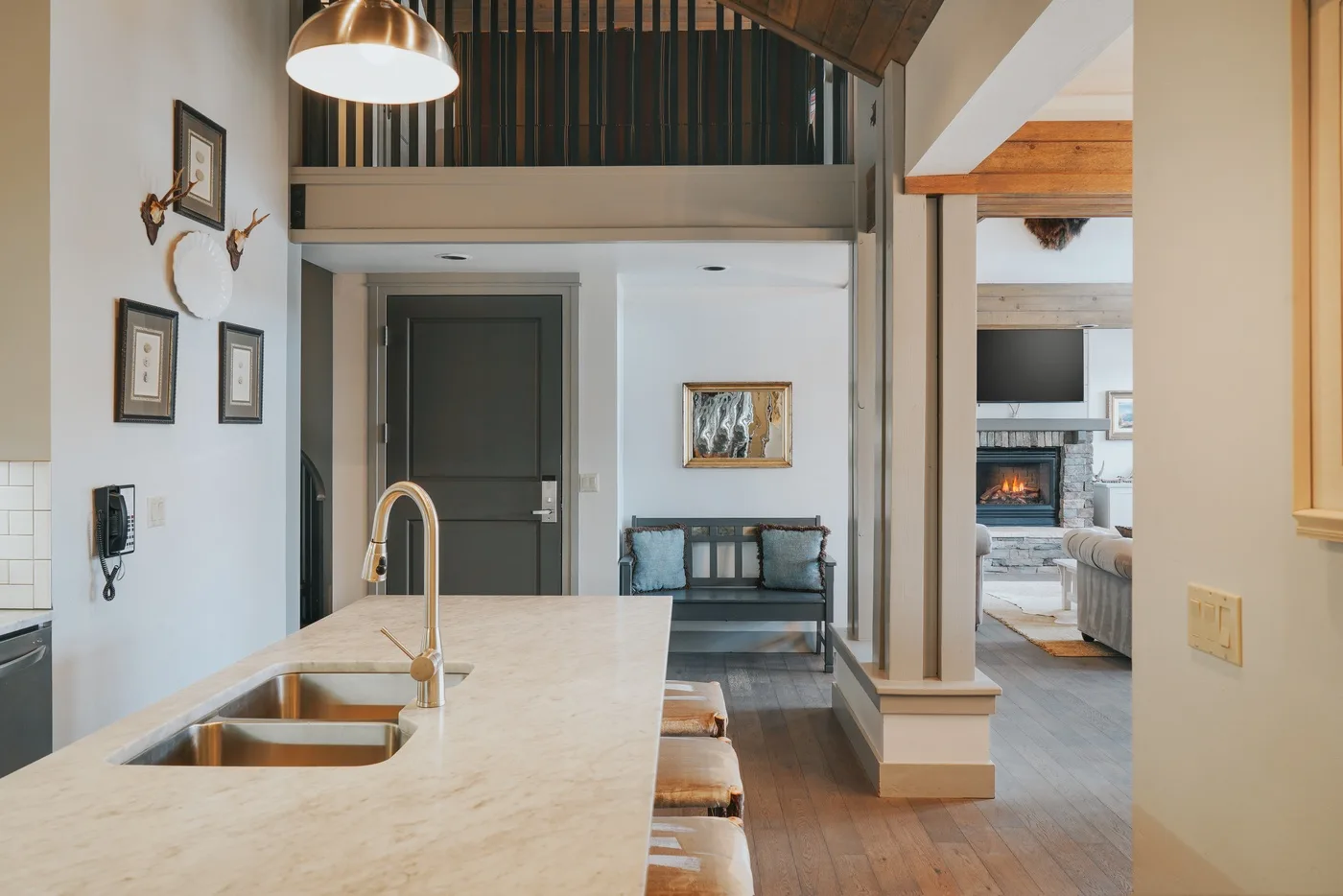 A kitchen island with a sink faces a small seating area and an open living room.