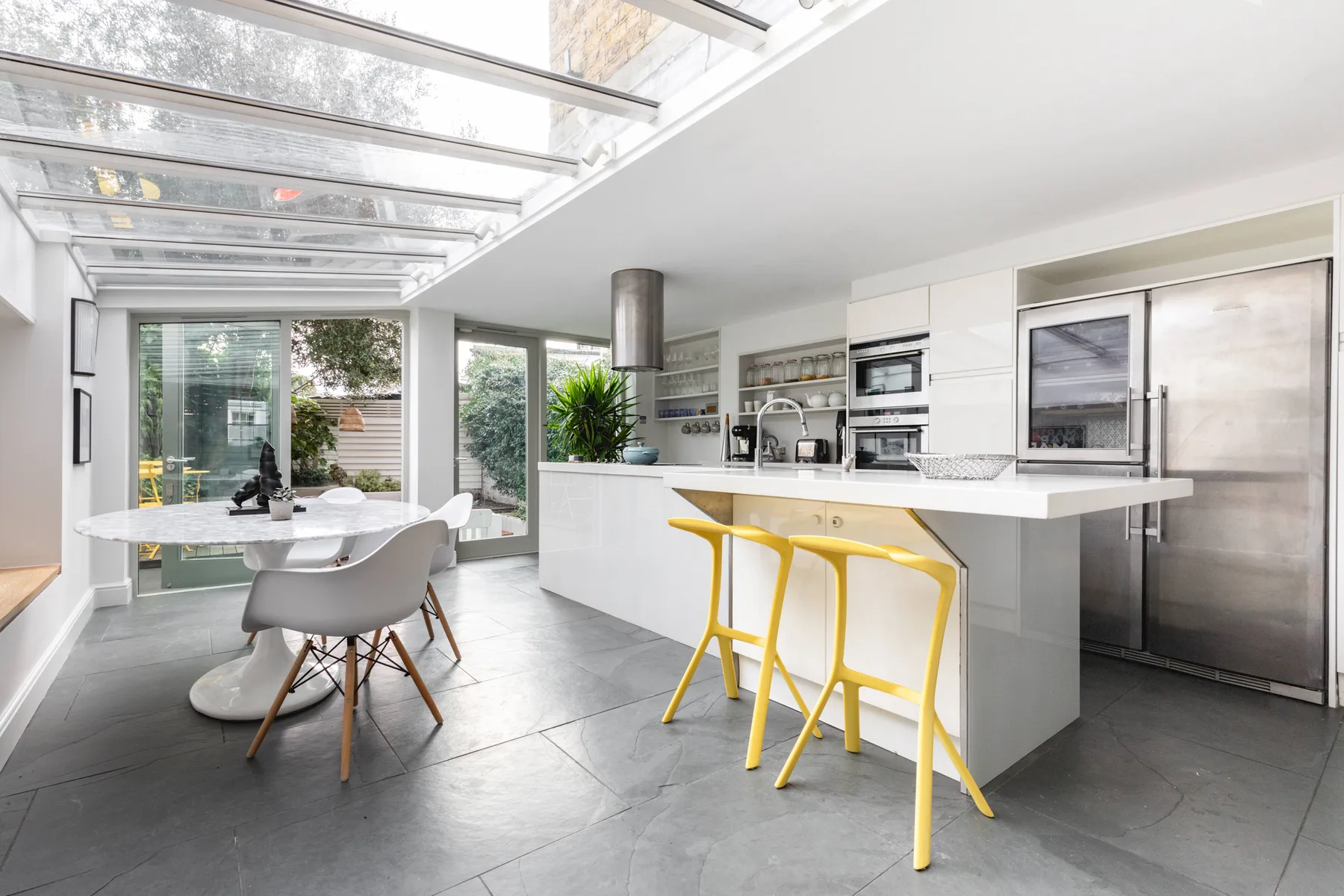 Una cocina y comedor modernos con una isla central y un techo de vidrio luminoso.