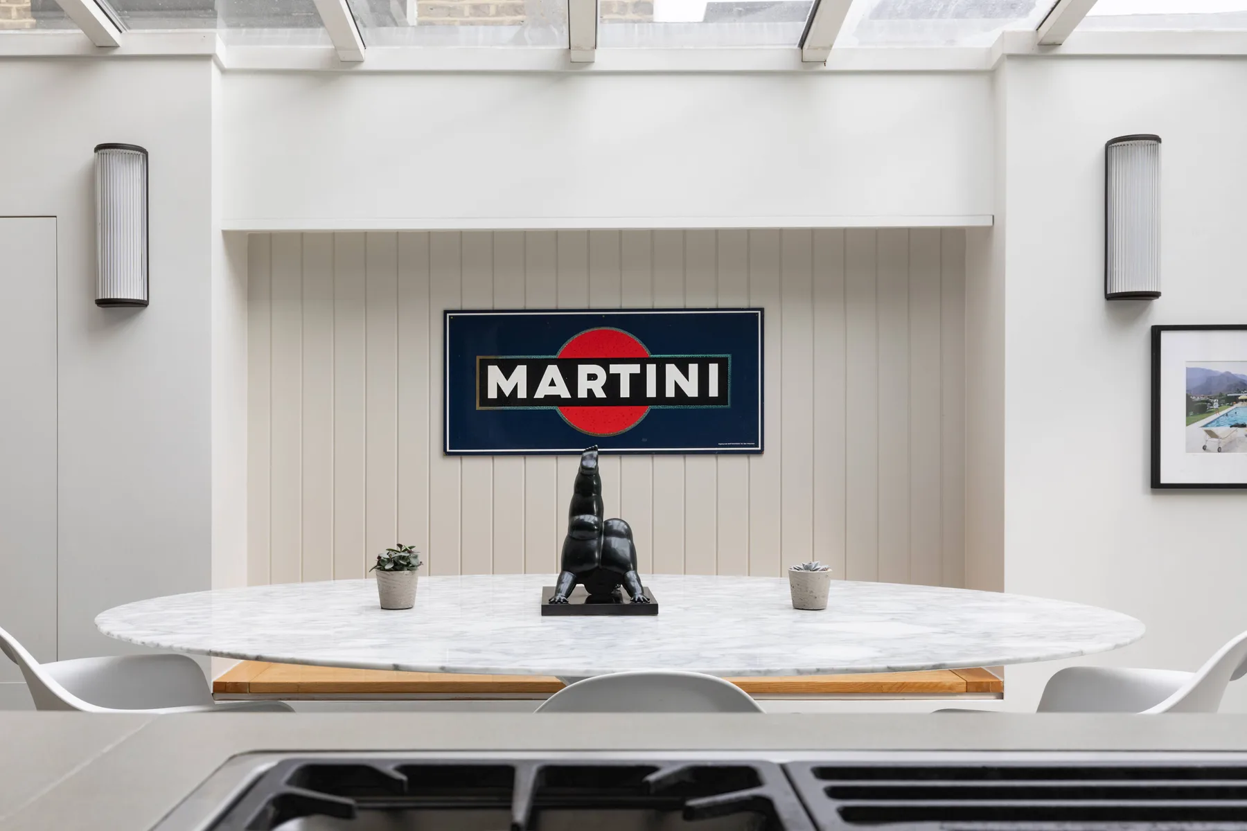 Un comedor luminoso con una mesa larga y un letrero de Martini en la pared.