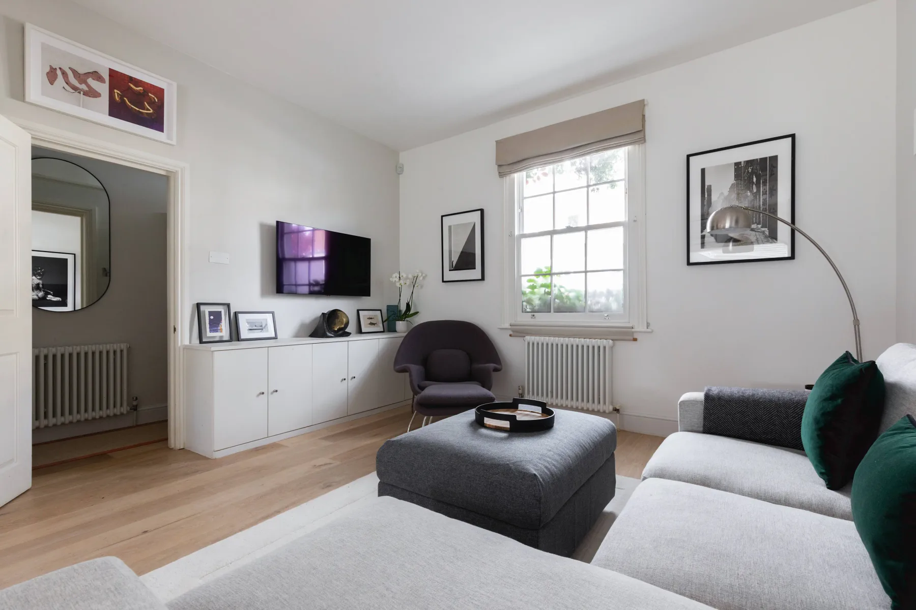 Una sala luminosa con asientos, un televisor y una ventana amplia.