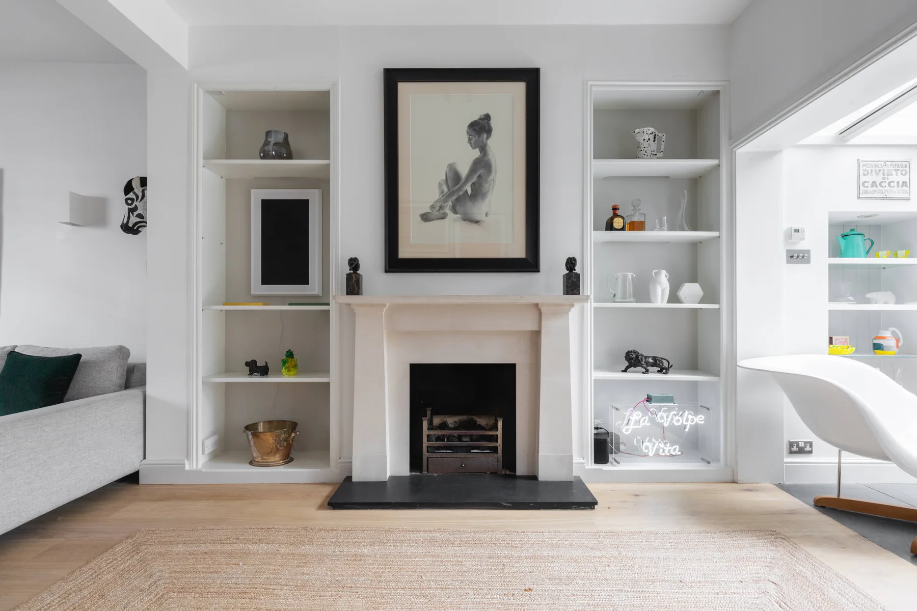 Una sala luminosa con chimenea, estanterías empotradas y una obra enmarcada.