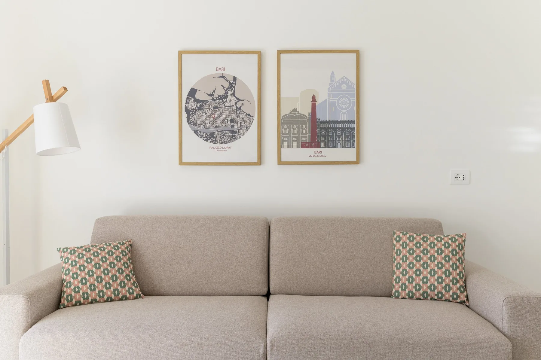Una zona de estar con un sofá, una lámpara de pie y cuadros en la pared.