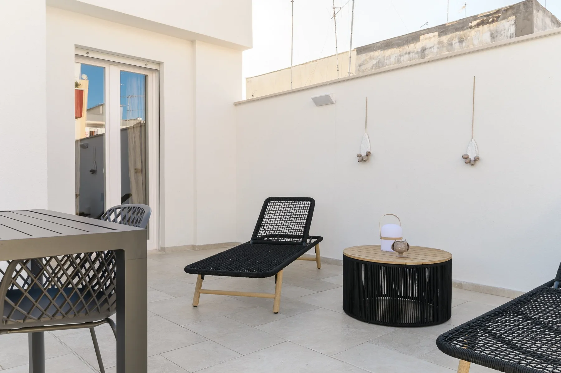 Una terraza en la azotea con asientos negros y una mesa redonda.