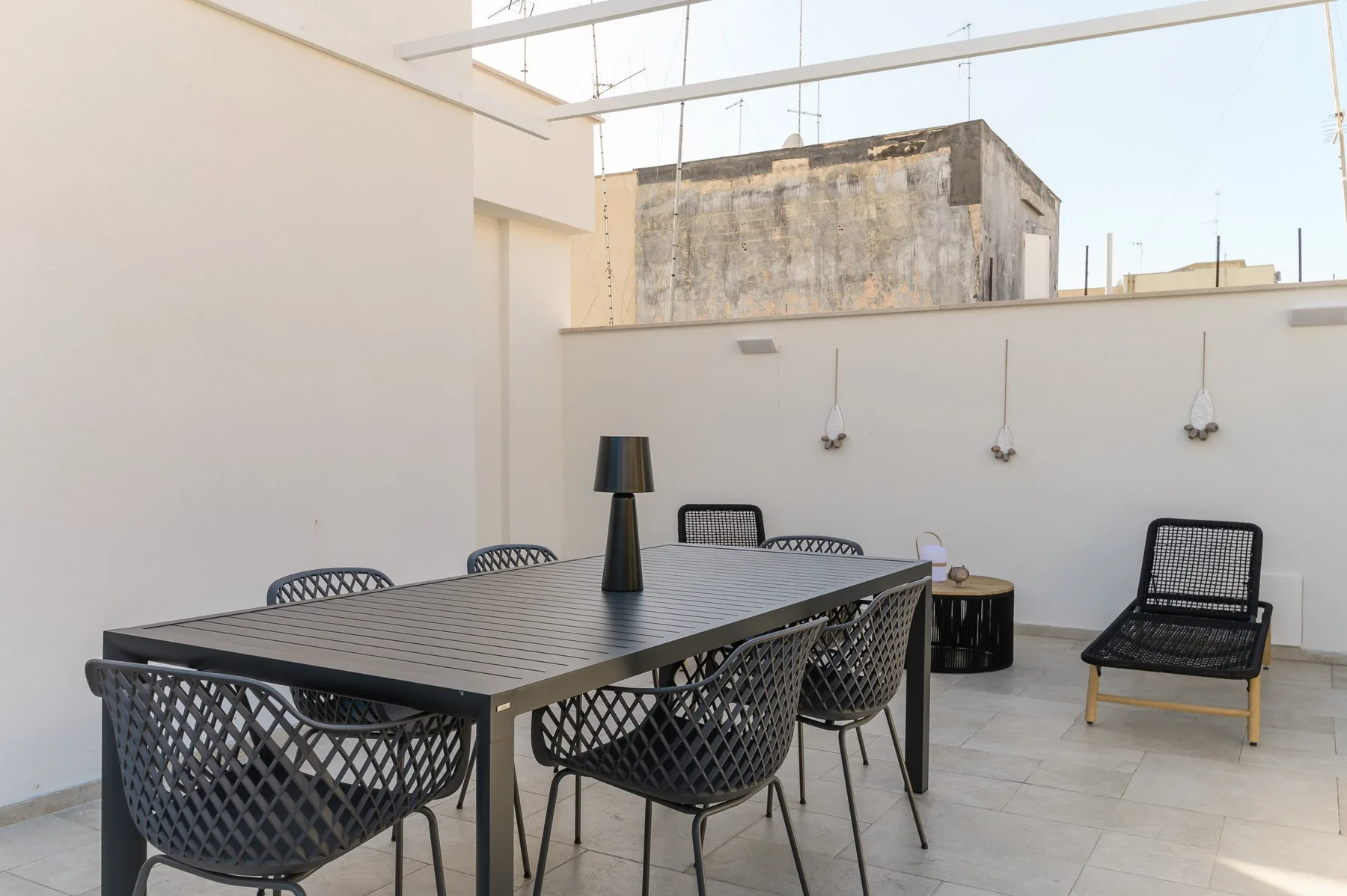 Un comedor al aire libre con una mesa larga y asientos de mimbre.