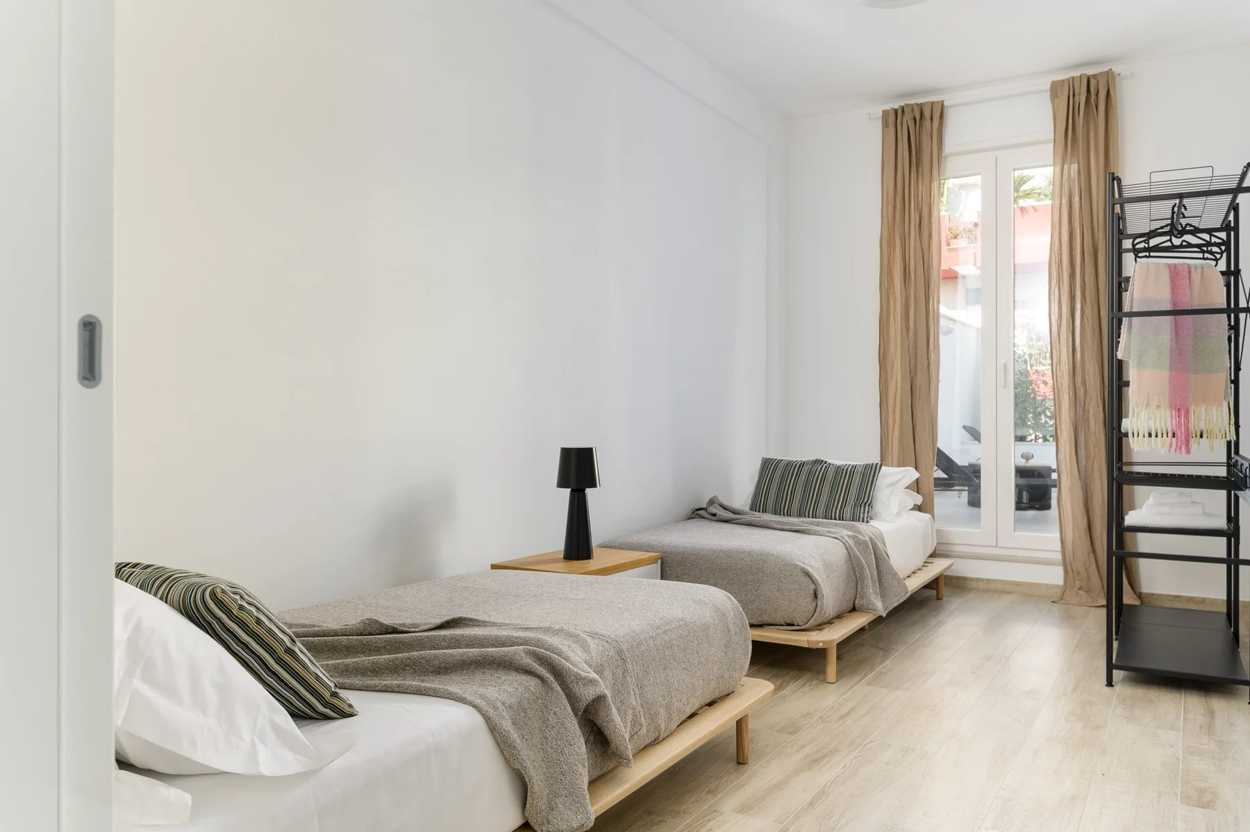 Un dormitorio luminoso con dos camas y una ventana enmarcada por cortinas.